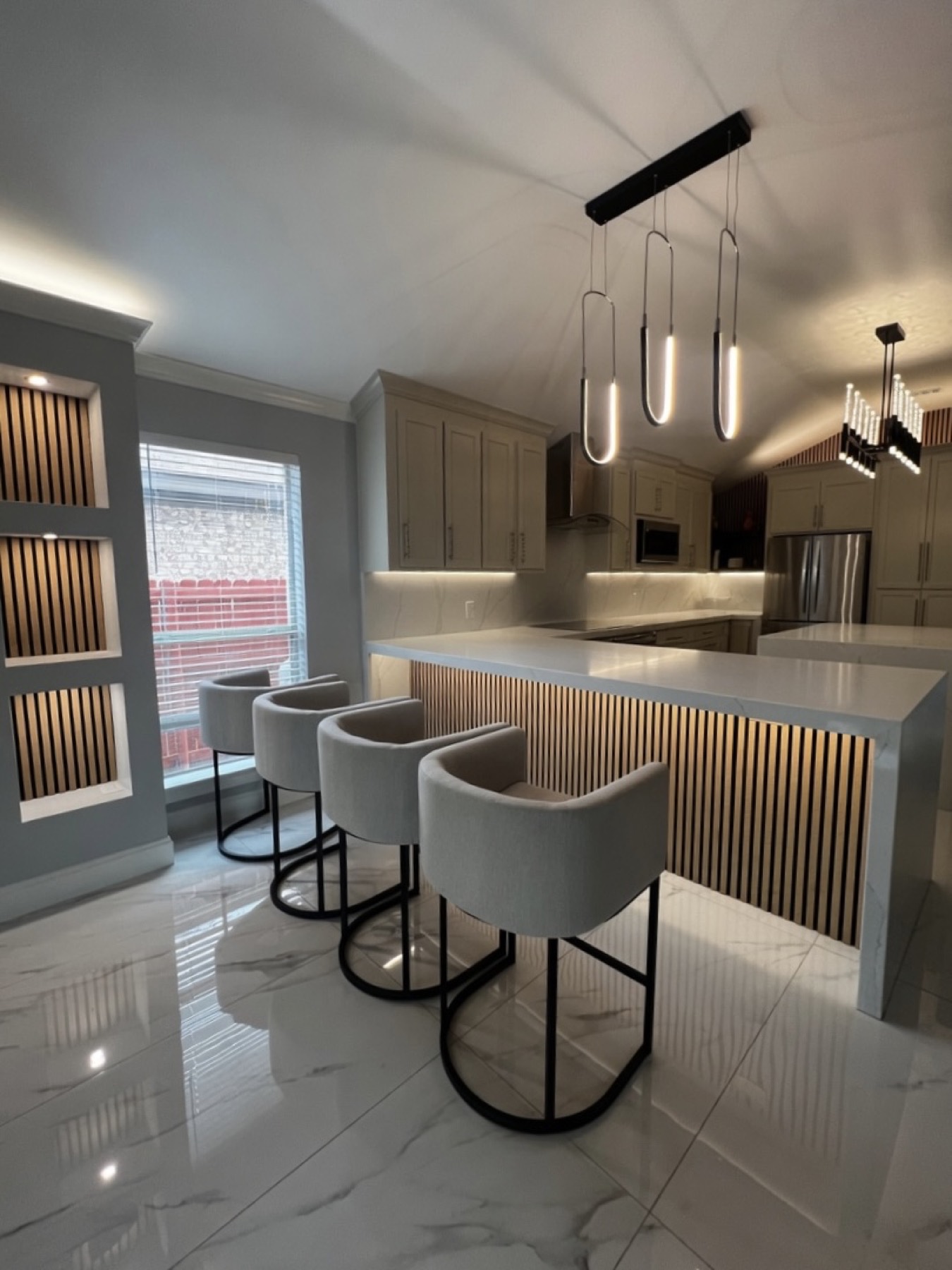 Kitchen bar with backlit wood slat waterfall island and halo pendants