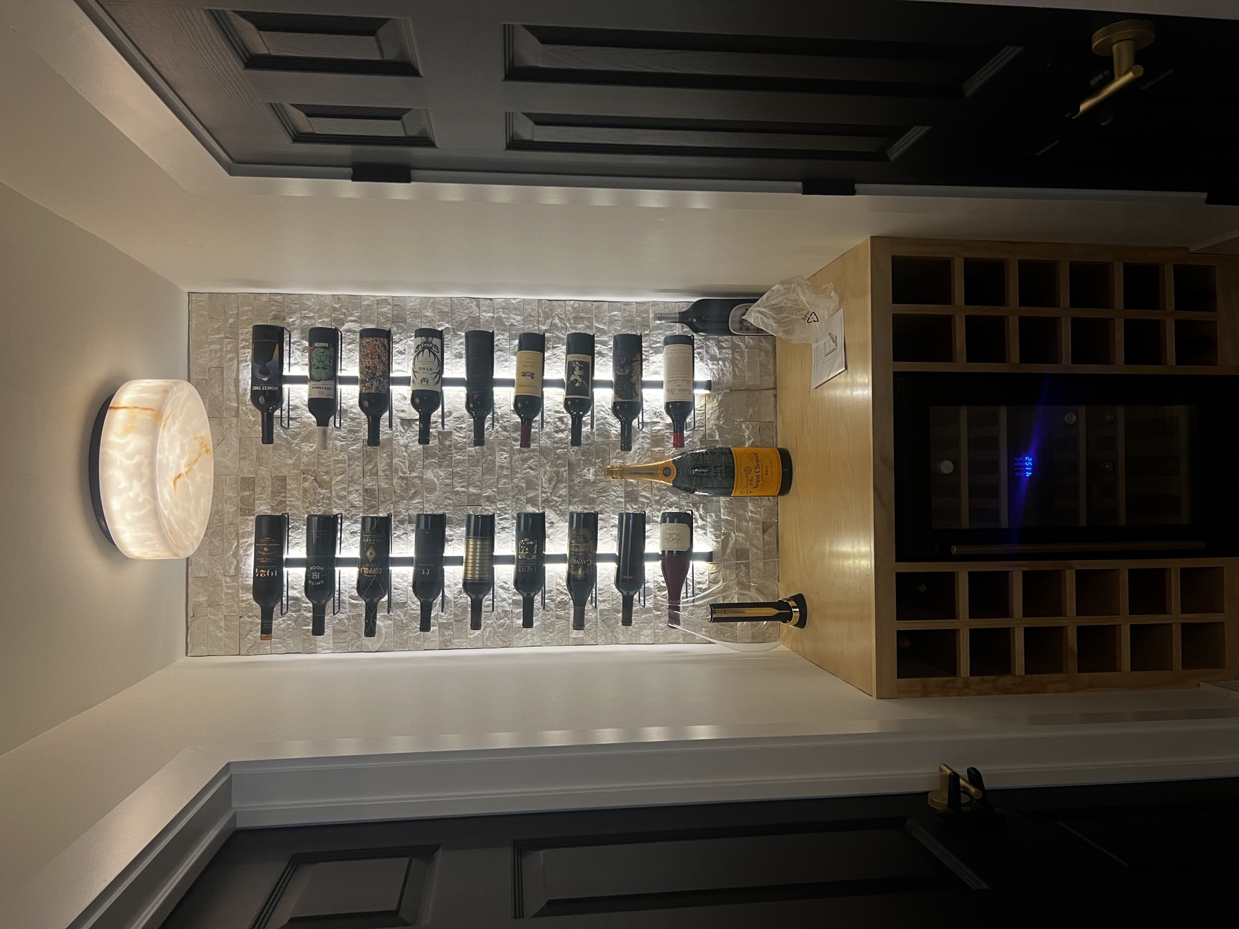 Stone cellar nook with LED rail-lit wine bottles and onyx ceiling light
